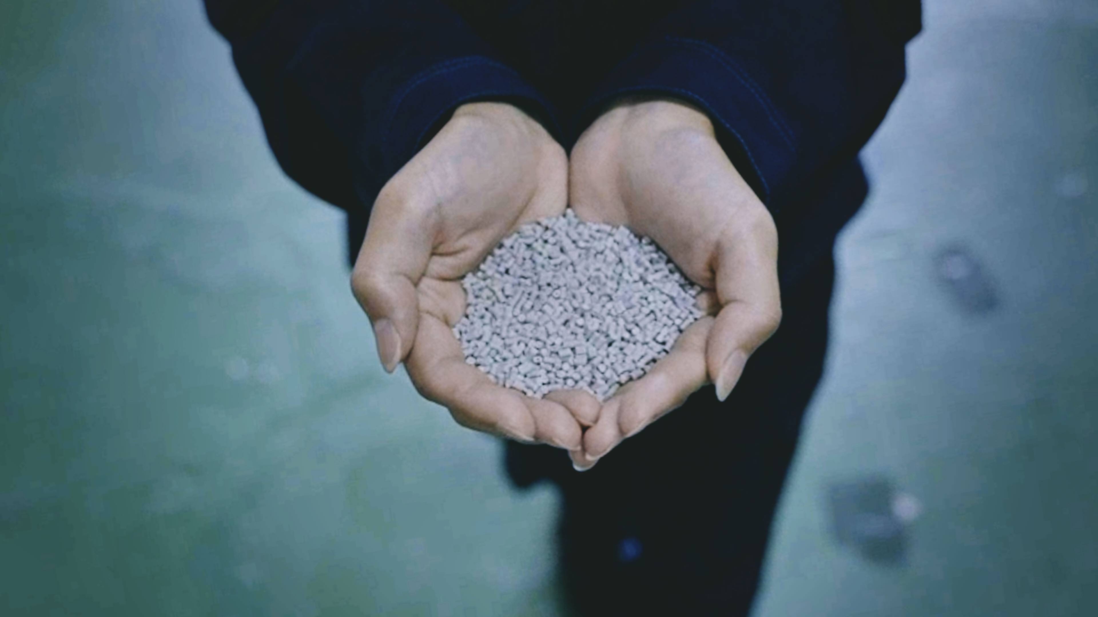 Material made from discarded scallop shells, held in someone's hands