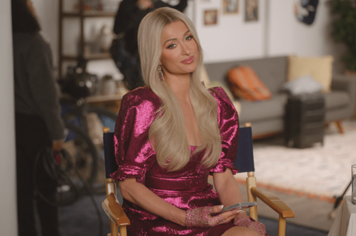 Paris Hilton sitting down in a sparkly hot pink dress