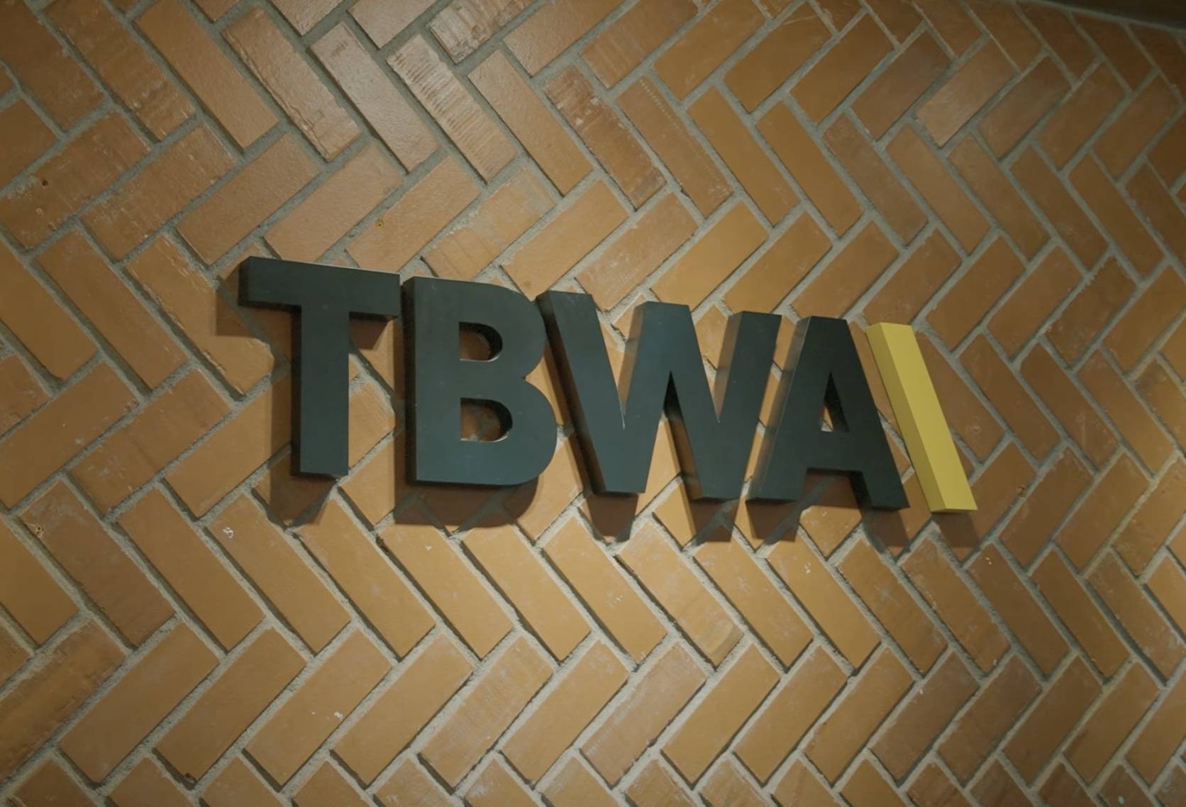 TBWA\ logo on brown brick wall