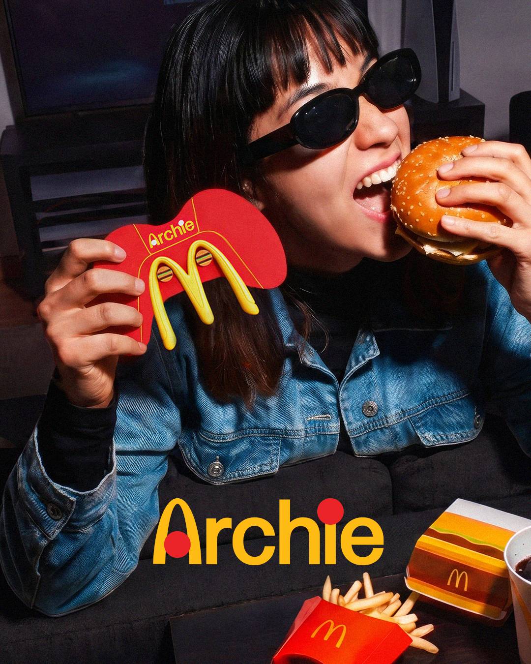 A girl takes a bite of a Big Mac while holding a McDonald's game controller
